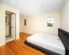 Bedroom featuring vaulted ceiling, french doors, hardwood / wood-style floors, and an inviting chandelier