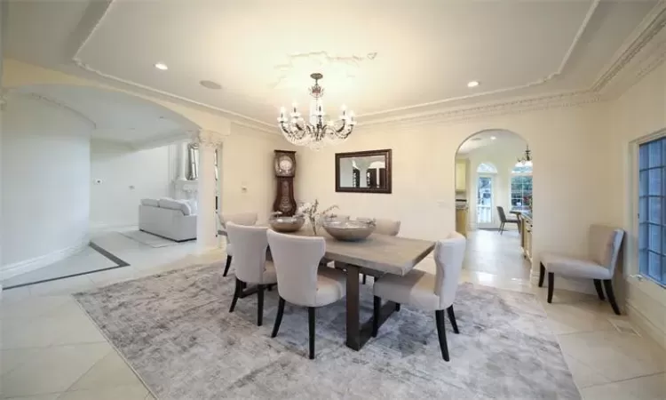 Dining area featuring a chandelier, light tile patterned floors, and ornamental molding