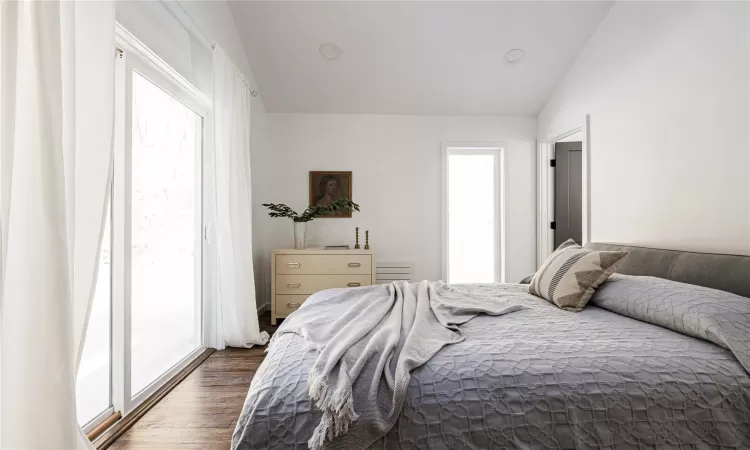 Bedroom featuring access to outside, dark wood-type flooring, and lofted ceiling