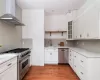 Kitchen with sink, wall chimney range hood, appliances with stainless steel finishes, and tasteful backsplash