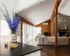 Living room featuring ceiling fan, vaulted ceiling, wooden walls, a stone fireplace, and dark hardwood / wood-style flooring