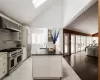 Kitchen with sink, a kitchen island with sink, premium appliances, high vaulted ceiling, and wall chimney exhaust hood