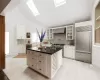 Kitchen with a skylight, premium appliances, a kitchen island, wall chimney exhaust hood, and white cabinets