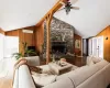 Living room with vaulted ceiling, hardwood / wood-style flooring, and a stone fireplace