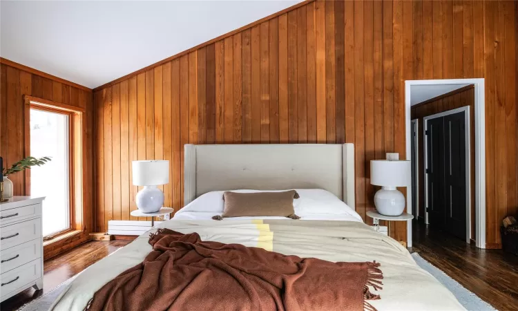 Bedroom with dark hardwood / wood-style floors and wood walls