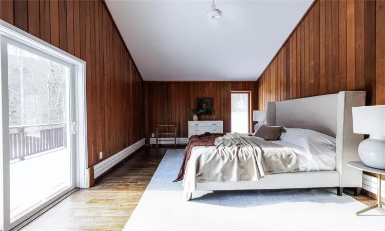 Bedroom with wood-type flooring, access to outside, and wooden walls