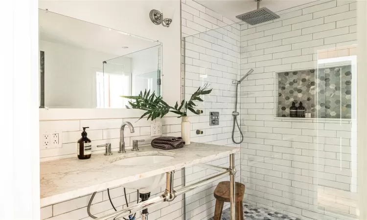 Bathroom with a tile shower, tasteful backsplash, and sink