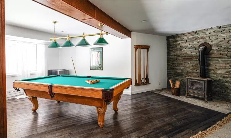 Game room with beam ceiling, billiards, dark hardwood / wood-style floors, and a wood stove