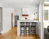 Kitchen featuring white cabinets, high end refrigerator, light hardwood / wood-style flooring, and a kitchen breakfast bar