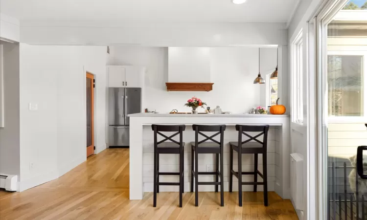 Kitchen featuring white cabinets, high end refrigerator, light hardwood / wood-style flooring, and a kitchen breakfast bar