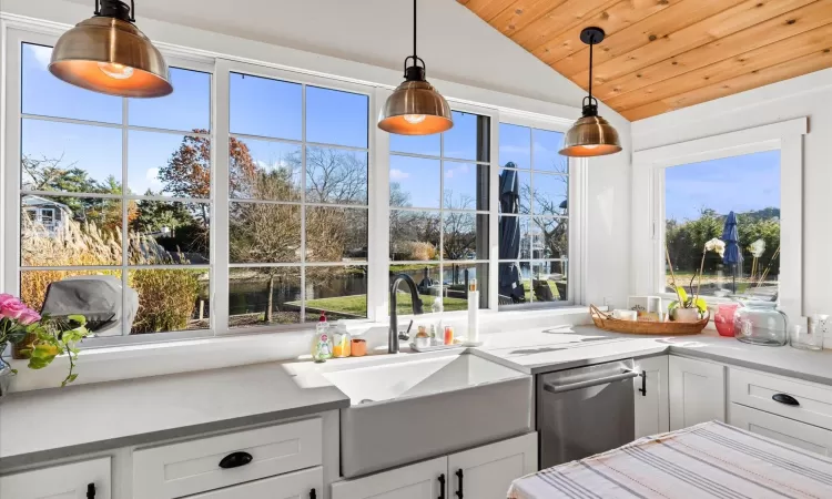 Kitchen featuring lofted ceiling, white cabinetry, hanging light fixtures, and wood ceiling