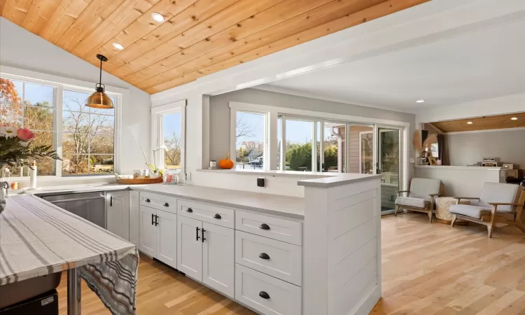 Kitchen featuring pendant lighting, dishwasher, white cabinetry, wood ceiling, and light hardwood / wood-style floors