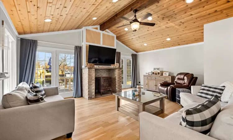 Living room with lofted ceiling with beams, plenty of natural light, light hardwood / wood-style flooring, and wood ceiling