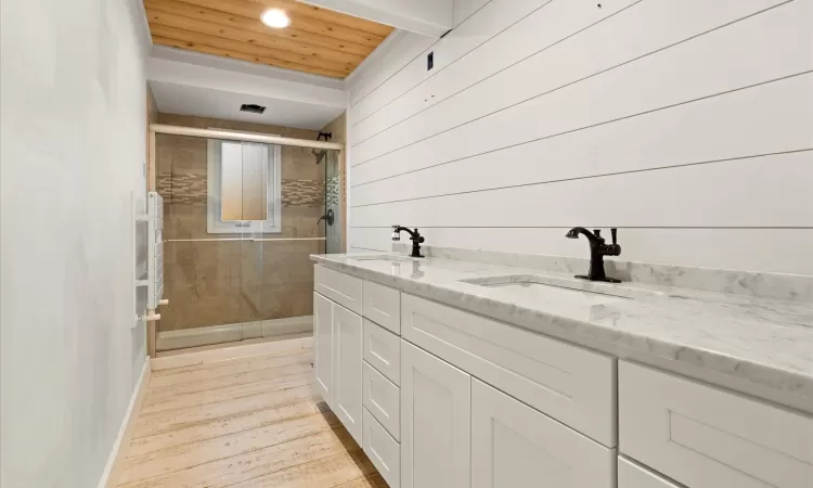 Bathroom featuring walk in shower, vanity, wood ceiling, and wooden walls