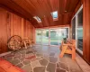 Unfurnished room featuring wooden ceiling, lofted ceiling with skylight, and wooden walls