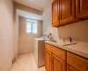 Laundry area featuring light tile patterned floors, cabinets, washer and dryer, and sink