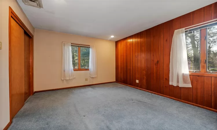 Unfurnished room featuring light colored carpet and wood walls