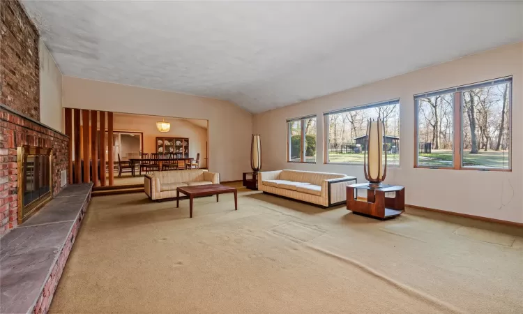 Carpeted living room with vaulted ceiling and a fireplace