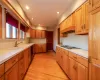 Kitchen with black appliances, light wood-type flooring, sink, and custom exhaust hood