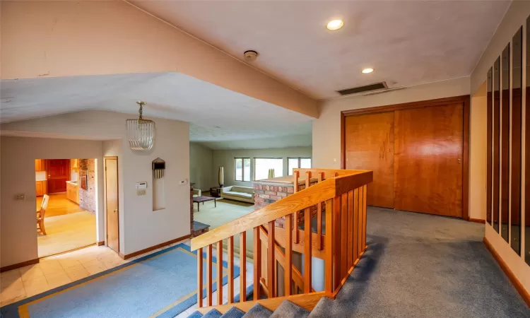 Corridor with lofted ceiling, carpet, and an inviting chandelier