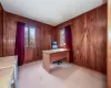 Office area featuring light colored carpet and wood walls