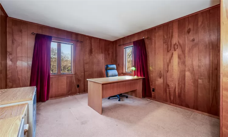 Office area featuring light colored carpet and wood walls