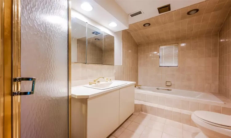 Bathroom featuring toilet, vanity, tile walls, and tile patterned floors