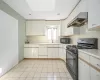 Kitchen featuring sink, light tile patterned flooring, black appliances, and white cabinets