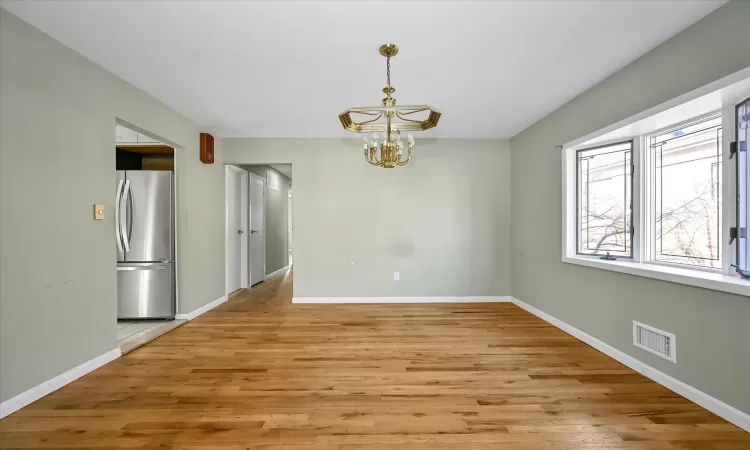 Unfurnished dining area featuring a notable chandelier and light wood-type flooring