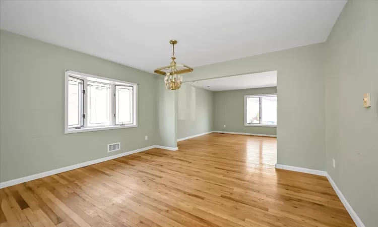 Unfurnished room featuring a notable chandelier and light hardwood / wood-style flooring