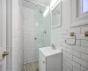 Bathroom featuring vanity, tile walls, and a tile shower