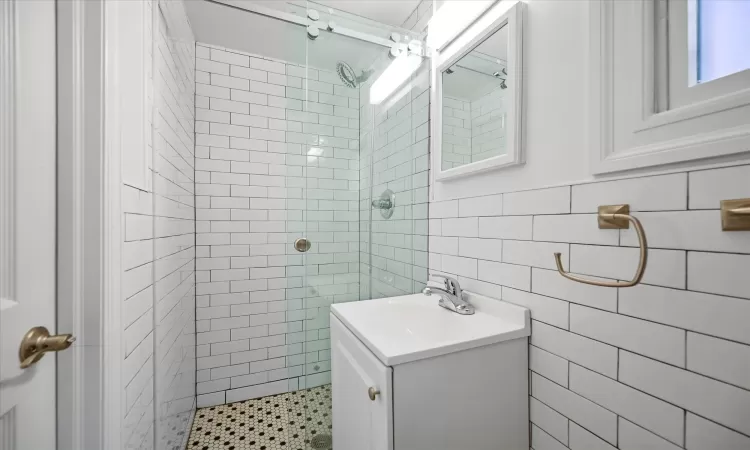 Bathroom featuring vanity, tile walls, and a tile shower