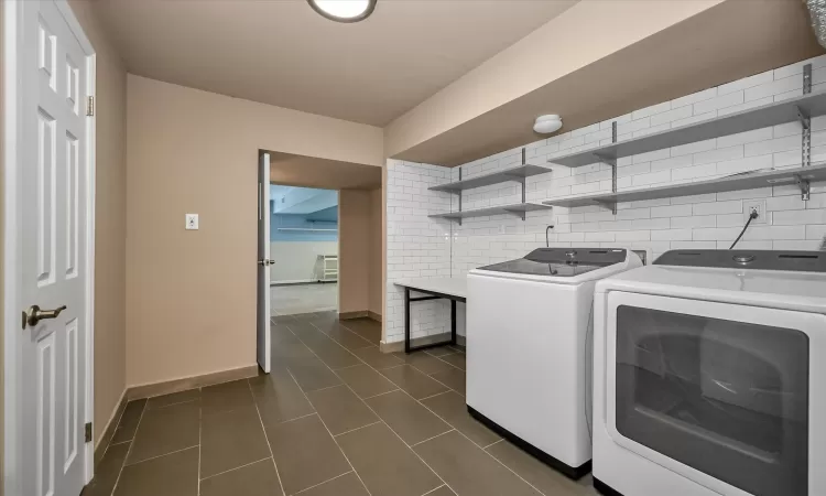 Clothes washing area featuring dark tile patterned flooring and separate washer and dryer