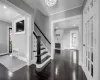 Entryway with a fireplace, dark hardwood / wood-style flooring, crown molding, and an inviting chandelier