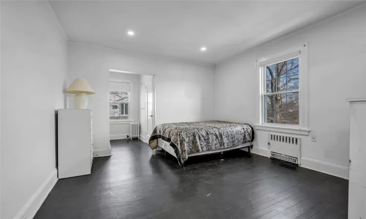 Bedroom with dark wood-type flooring and radiator heating unit