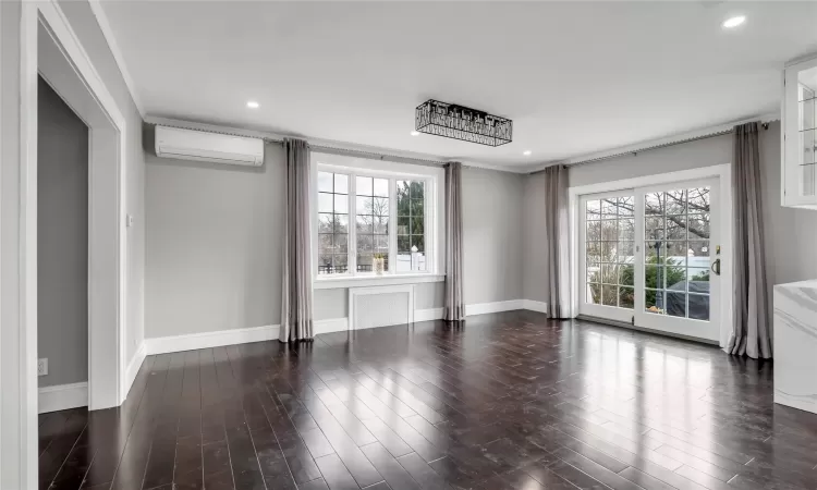 Unfurnished room with a wall unit AC, dark hardwood / wood-style flooring, and ornamental molding