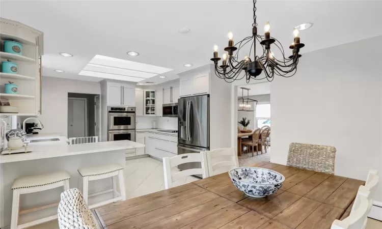 Tiled dining area with sink, baseboard heating, and a chandelier