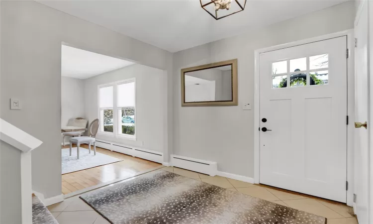 Entryway featuring a baseboard radiator, a wealth of natural light, and light tile patterned floors