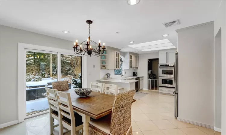 Dining room featuring sink, a notable chandelier, and light tile patterned floors