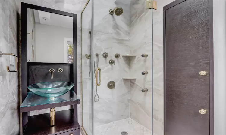 Bathroom with tile walls, sink, toilet, and walk in shower