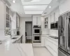 Kitchen featuring appliances with stainless steel finishes, sink, white cabinetry, light tile patterned floors, and light stone countertops