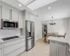 Kitchen featuring baseboard heating, decorative backsplash, white cabinets, stainless steel appliances, and light tile patterned flooring