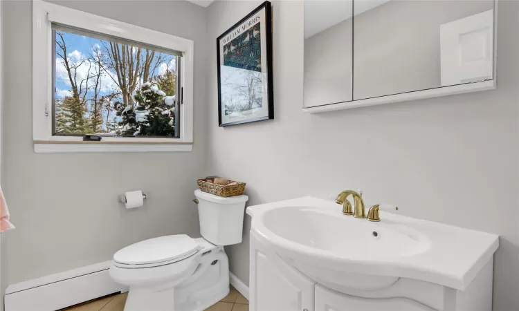 Bathroom with toilet, a baseboard heating unit, and tile patterned flooring