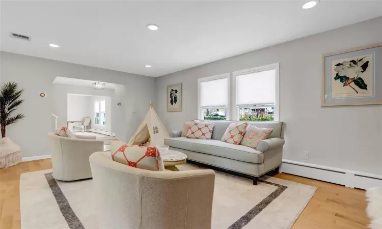 Living room with light hardwood / wood-style floors and baseboard heating