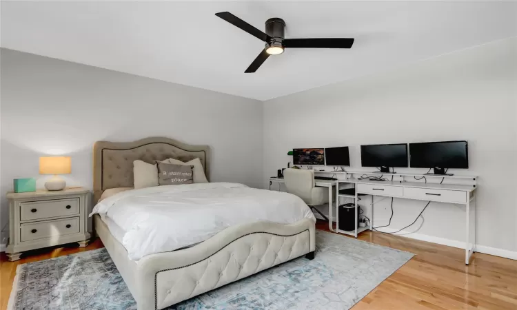 Bedroom with ceiling fan, a baseboard radiator, and light hardwood / wood-style flooring