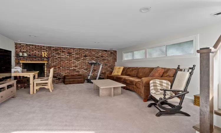 Living room featuring light colored carpet and brick wall