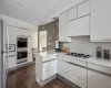 Kitchen with white appliances, white cabinetry, decorative backsplash, dark hardwood / wood-style floors, and kitchen peninsula