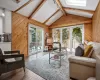 Living room with vaulted ceiling with skylight, light hardwood / wood-style flooring, and wooden walls