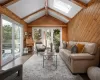 Living room featuring vaulted ceiling with skylight, hardwood / wood-style floors, and wooden walls