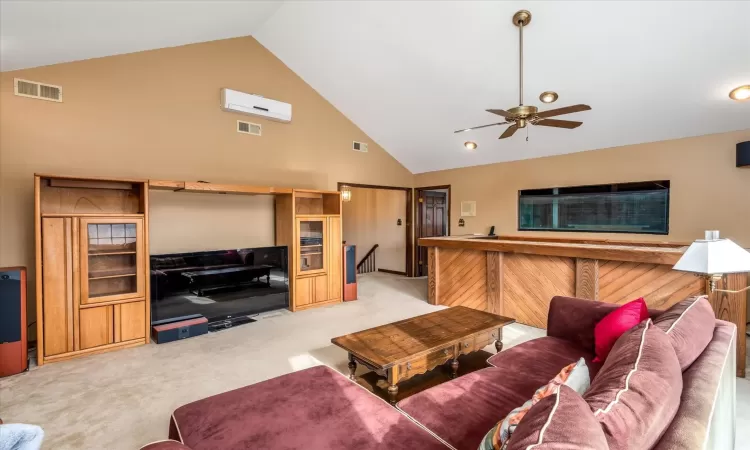 Carpeted living room featuring ceiling fan and high vaulted ceiling